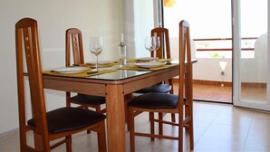 Een eetgedeelte met een tafel voor vier personen, stoelen en uitzicht op buiten.