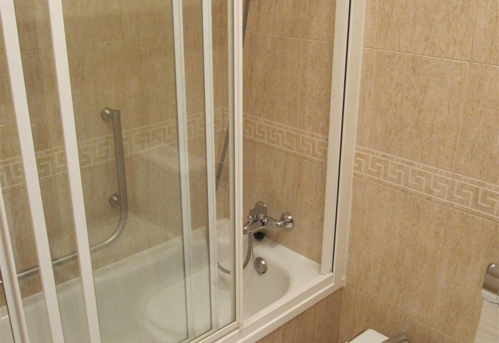 Un área de ducha con paredes de vidrio, que incluye una bañera, un cabezal de ducha y un grifo.