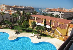 A hotel with a swimming pool, palm trees, and a view of the marina. - 'Fabulous sunny apartment' with Terrace (Almerimar)