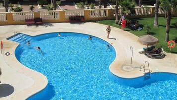 Una amplia piscina al aire libre con varias pistas de natación, un toldo y un puesto de socorristas.