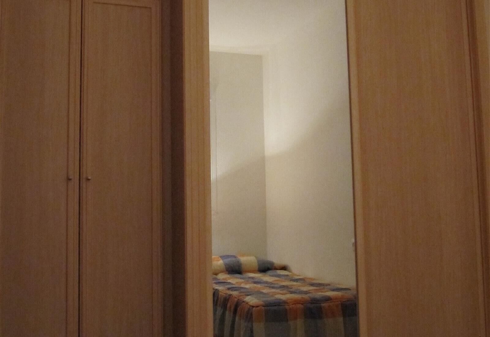 Ein Schlafzimmer mit einem Bett, einem Kleiderschrank und einem Spiegel.