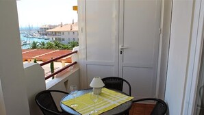 Een balkon met een tafel en stoelen, uitzicht op een jachthaven en een deur.
