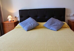 A bed with a quilted headboard, two pillows, a bedside lamp, and a wooden nightstand. - 'Fabulous sunny apartment' with Terrace (Almerimar)