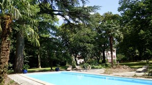 Una piscina envoltada d'arbres i mobles d'exterior.