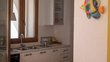 Een koelkast, een oven, een kookplaat, kookgerei, borden en bestek