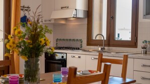Une cuisine avec des meubles blancs, une cuisinière, un évier et une fenêtre.