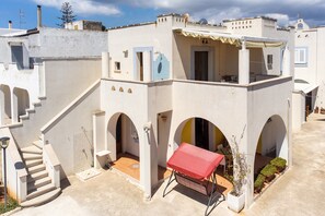 Ein weißes Gebäude mit einem roten Tisch, einer Treppe und einem kleinen Garten.