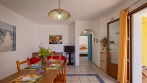 Un coin repas avec une table en bois, des chaises, un téléviseur et un tableau accroché au mur.