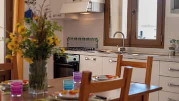 Een koelkast, een oven, een kookplaat, kookgerei, borden en bestek