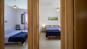 Une chambre avec deux lits, une petite table, une chaise et un tableau au mur.
