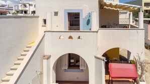 Un bâtiment avec un escalier, une petite fenêtre avec des volets et un auvent rouge.