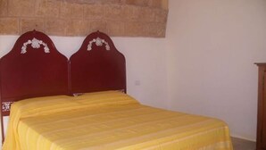 Ein Bett mit Holz Kopfteil und einer gelben Tagesdecke.