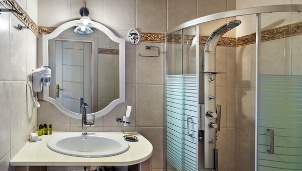 Un baño moderno con un espejo grande, un lavamanos y una ducha.
