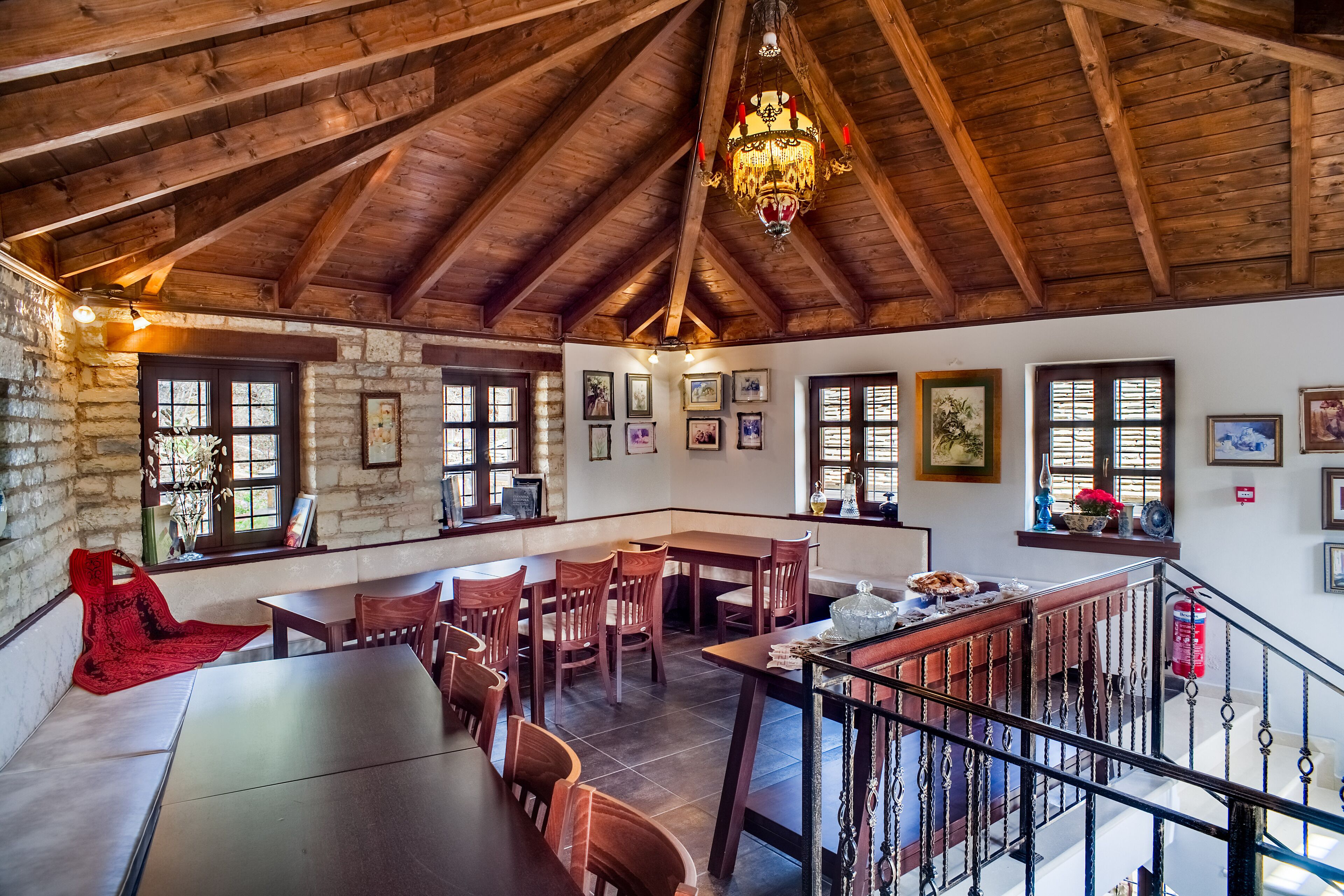 A spacious dining area with wooden tables and chairs, a chandelier, and framed artwork on the walls.