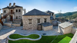 A stone building with multiple levels, a central staircase, and a well-maintained lawn. - Gioraldi Art Hotel (Zagori)