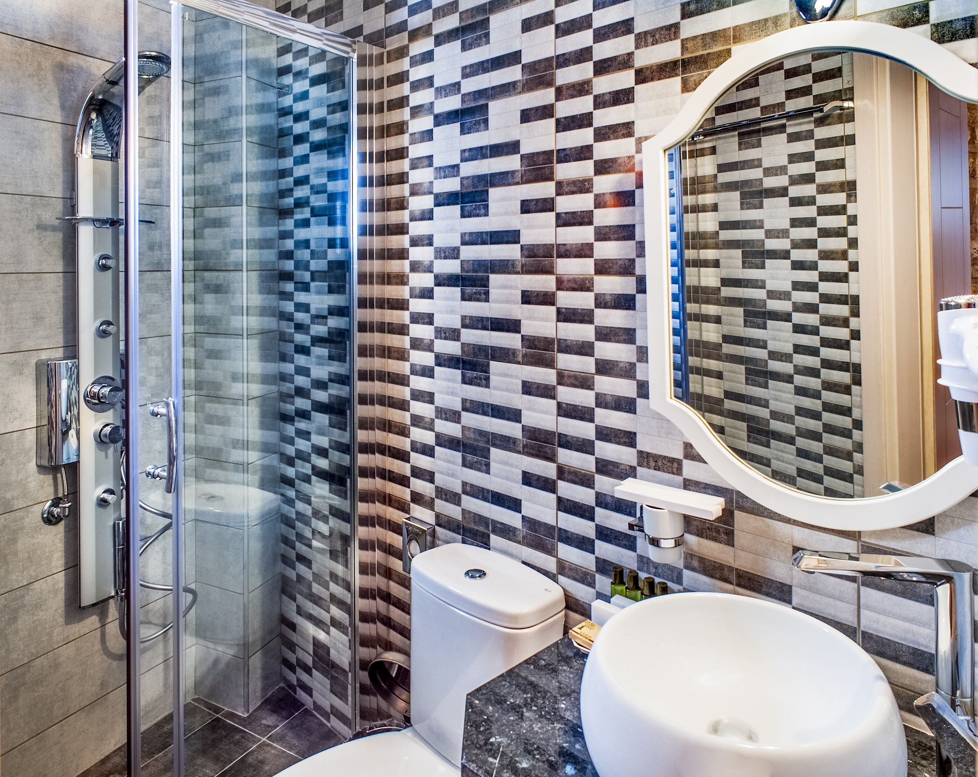 Un baño moderno con cabina de ducha de vidrio, inodoro y lavamanos con un espejo grande.