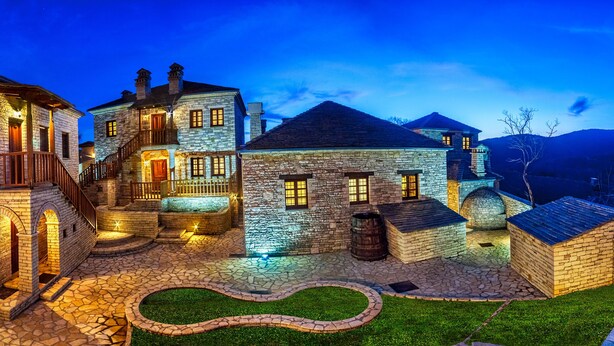 A stone building with multiple levels, a central courtyard, and a well-lit entrance. - Gioraldi Art Hotel (Zagori)