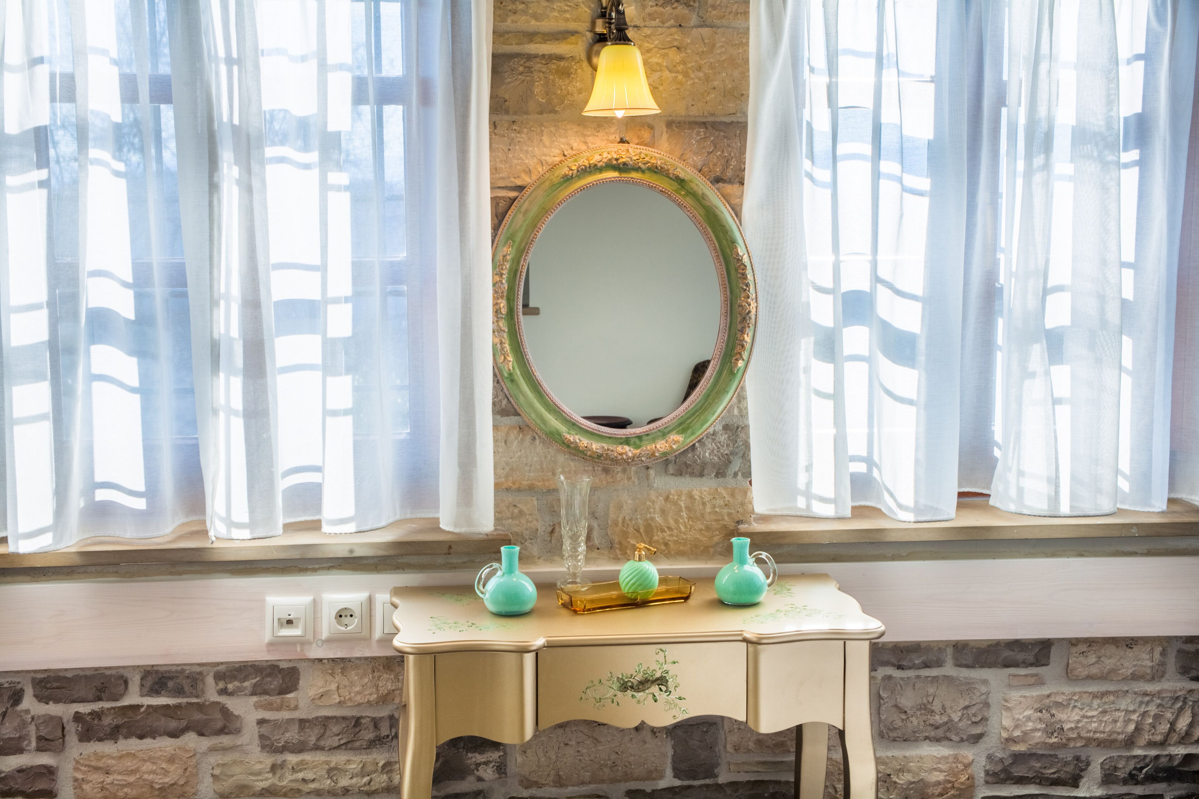 Un meuble-lavabo pour la salle de bain, doté d’un miroir, d’un luminaire et de trois vases décoratifs.