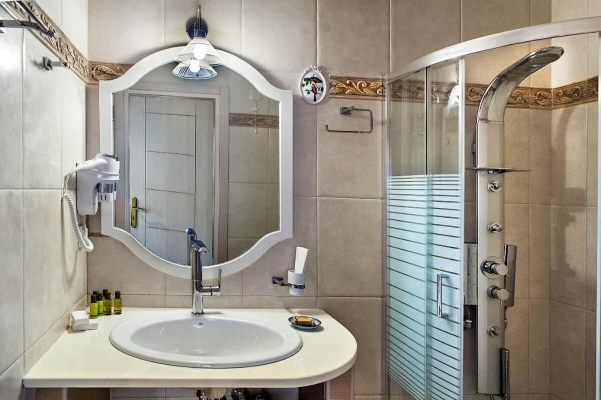 A bathroom with a sink, mirror, and shower.