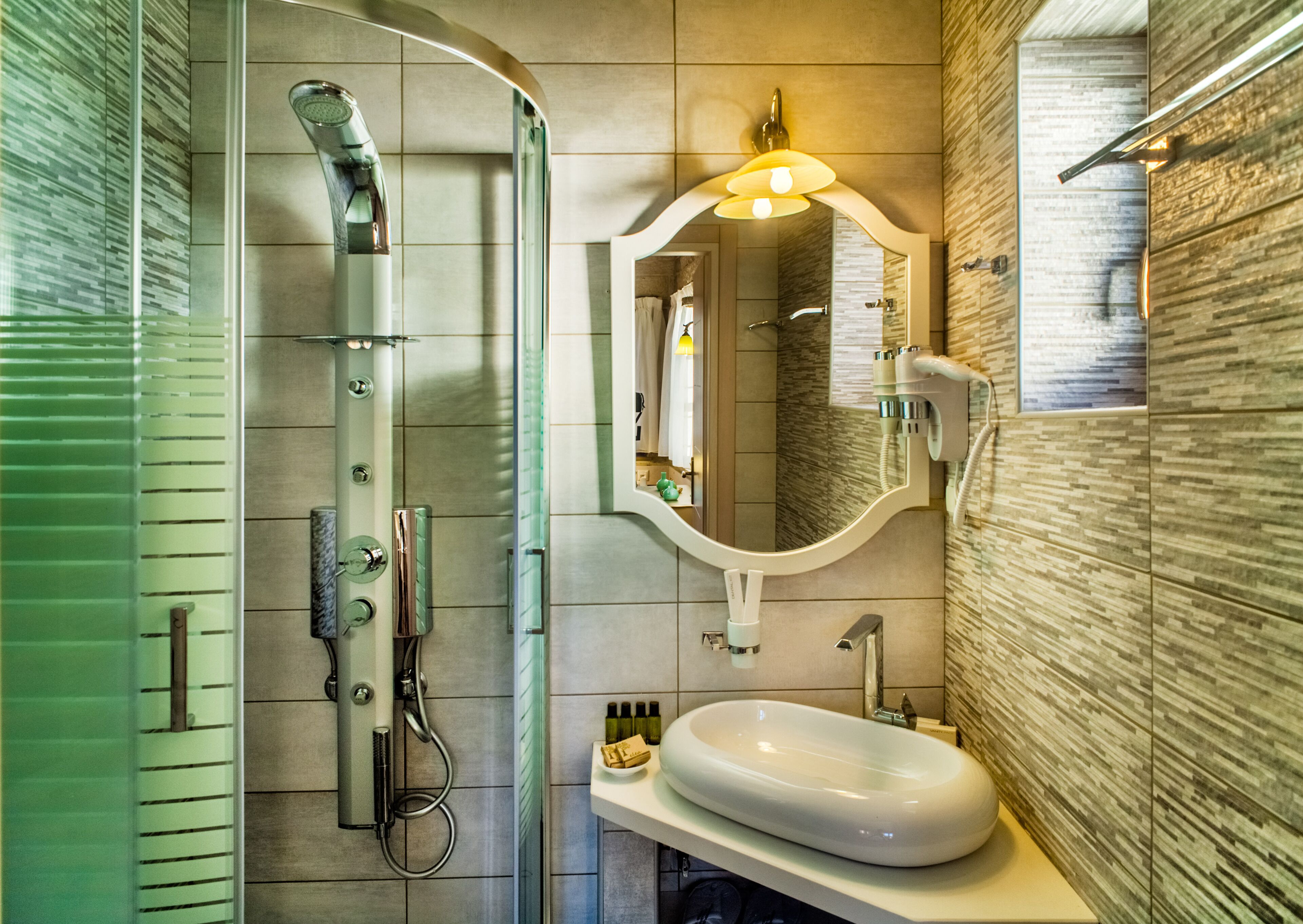 A modern bathroom with a glass-enclosed shower, a vanity with a sink, and a mirror with integrated lighting.