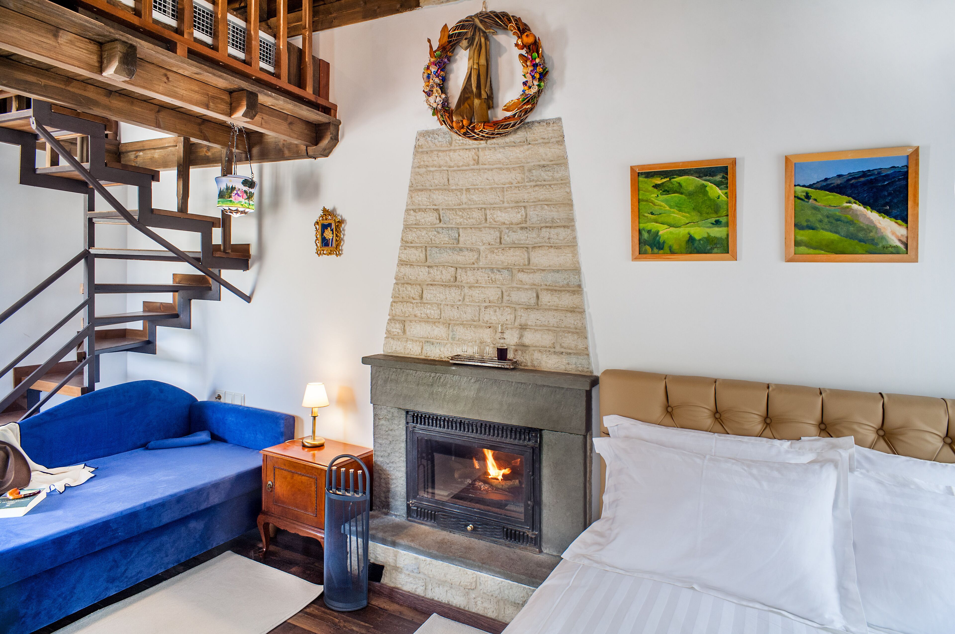 A living room with a fireplace, blue sofa, and a staircase.