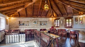 A spacious dining area with a high wooden ceiling and stone walls, featuring a long table and multiple chairs. - Gioraldi Art Hotel (Zagori)