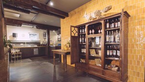 A restaurant with a tiled wall, a wooden cabinet with bottles, a table, and a counter. - EDELFUCHS-LODGE (Buehlertal)
