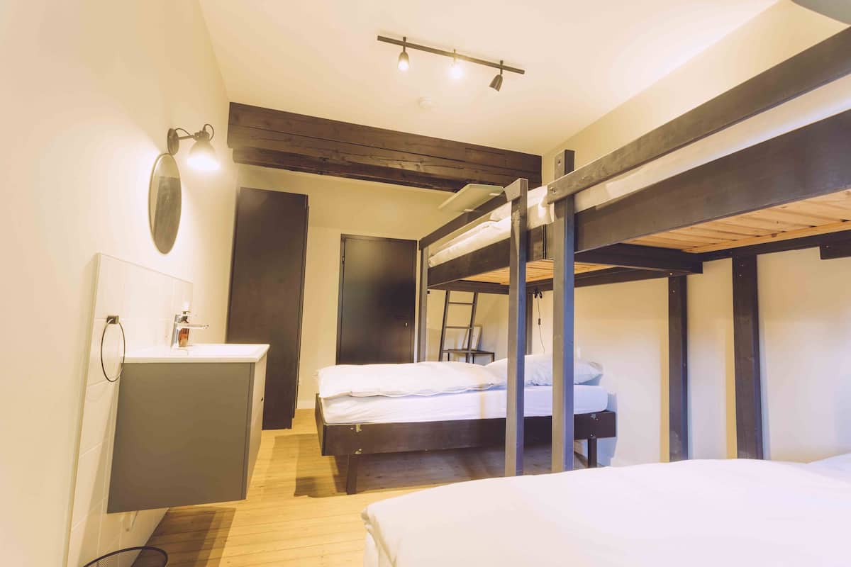 Una habitación con literas, un escritorio pequeño y un lavabo.