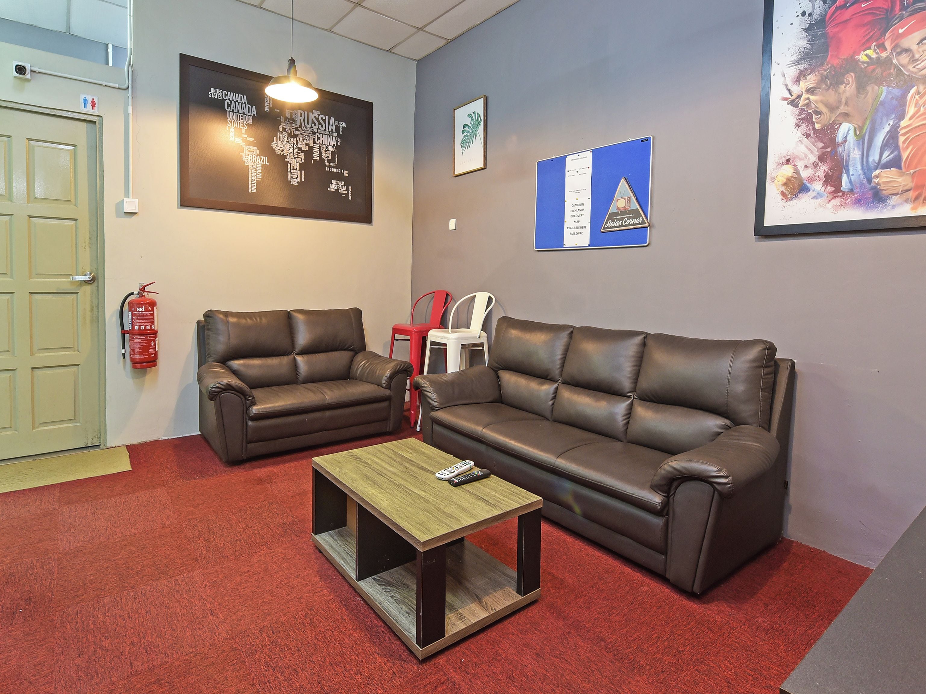 A room with two leather sofas, a wooden coffee table, and a red carpet.
