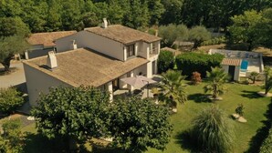 A two-story house with a tiled roof, surrounded by lush greenery and a small pool area. - Beautiful 10p villa with private pool, jacuzzi & tennis court (Vers-Pont-du-Gard)