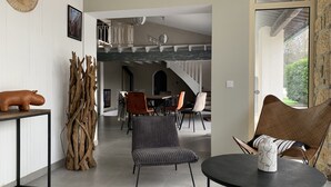 A modern interior with a dining area, a seating area with a round table, and a staircase leading to an upper level. - Beautiful 10p villa with private pool, jacuzzi & tennis court (Vers-Pont-du-Gard)