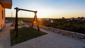 Une terrasse avec une balançoire, un petit espace de jeux et une vue sur le paysage environnant.