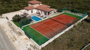 Une maison à deux étages avec un court de tennis et une piscine.
