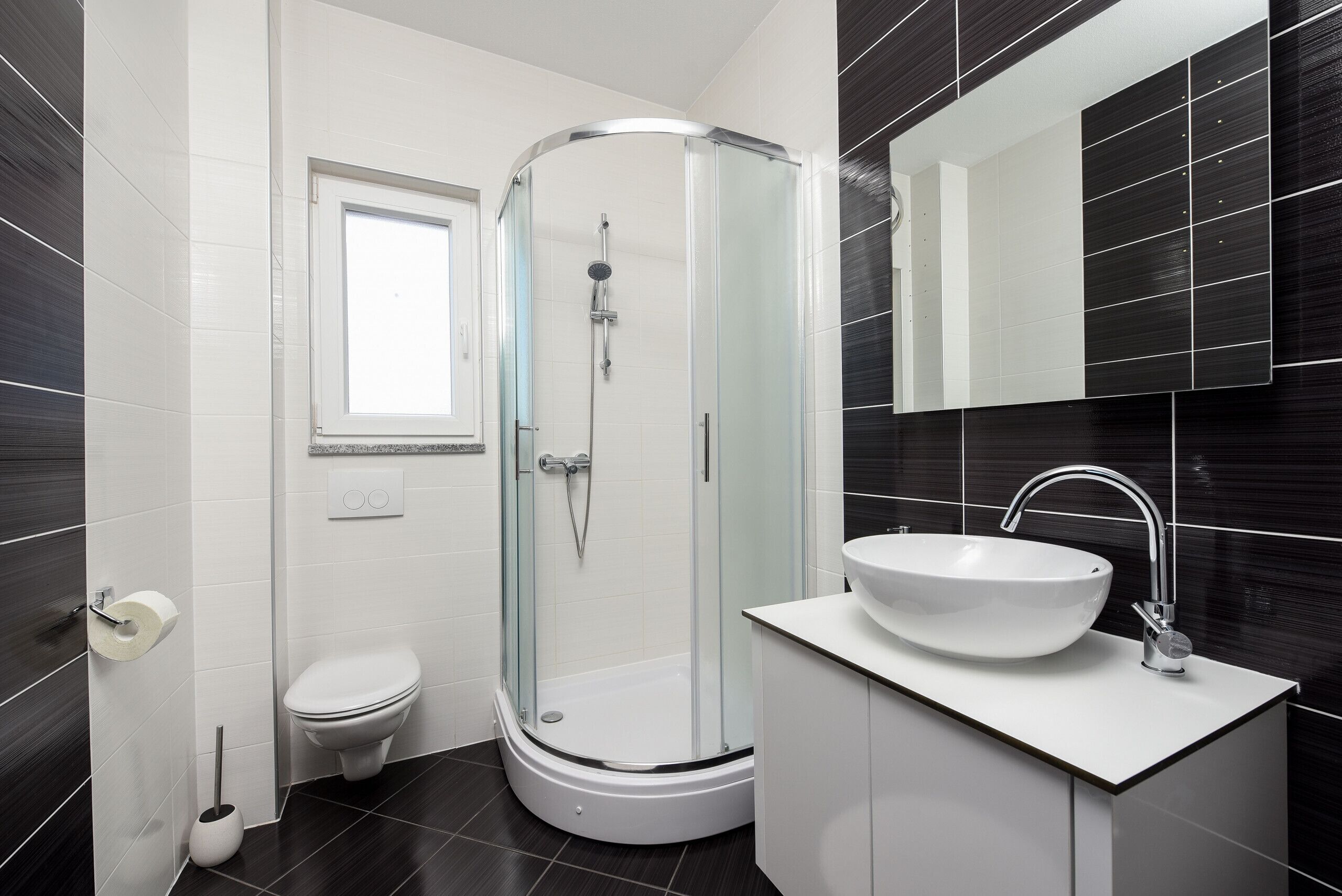 A modern bathroom with a glass-enclosed shower, a white sink, and a toilet.