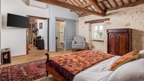 Una camera da letto con soffitto in legno, un letto grande, un armadio e una televisione.