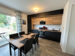 A modern kitchen with black cabinets, a wooden countertop, and a built-in microwave. - Modern Apartment for 2-4, 400m from Beach, Terrace, Parking, Quiet Area (Sarzeau)