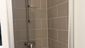 A shower with a handheld showerhead and a wall-mounted faucet.