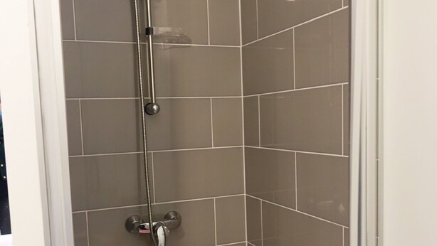 A shower with a handheld showerhead and a wall-mounted faucet. - Modern Apartment for 2-4, 400m from Beach, Terrace, Parking, Quiet Area (Sarzeau)