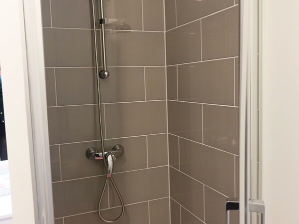 A shower with a handheld showerhead and a wall-mounted faucet. - Modern Apartment for 2-4, 400m from Beach, Terrace, Parking, Quiet Area (Sarzeau)