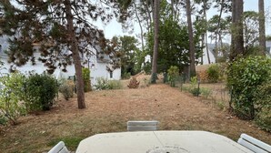 An outdoor patio with a concrete table and chairs, surrounded by trees and a grassy area. - Modern Apartment for 2-4, 400m from Beach, Terrace, Parking, Quiet Area (Sarzeau)