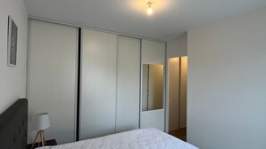 A bedroom with a bed, a bedside lamp, a wardrobe, and a mirror.