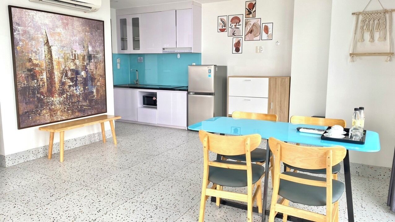 A compact kitchen with white cabinets, a blue countertop, and a stainless steel refrigerator.