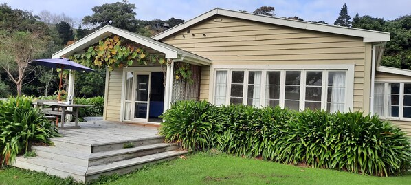 A two-story house with a front porch, a covered patio, and a well-maintained garden.