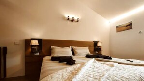 A neatly made bed with a quilt, two bedside lamps, and a nightstand with a lamp. - BIG HOUSE, rent in mountain (Bosco Chiesanuova)