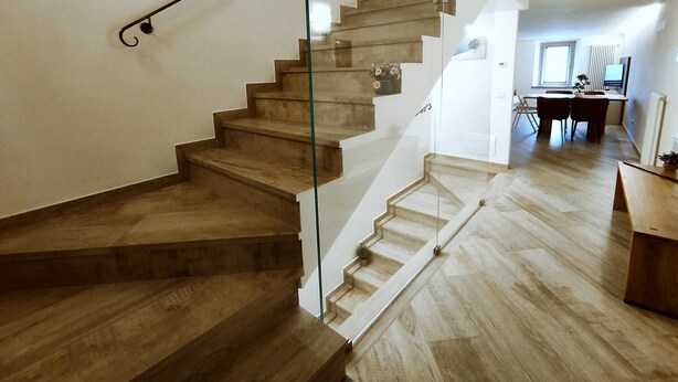 A modern staircase with glass railings leading to a dining area with a table and chairs. - BIG HOUSE, rent in mountain (Bosco Chiesanuova)