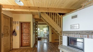 Un intérieur en bois avec un escalier, une cheminée et un couloir menant à une autre pièce.