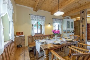Une table de salle à manger en bois, mise avec des assiettes, des verres et un vase de fleurs.