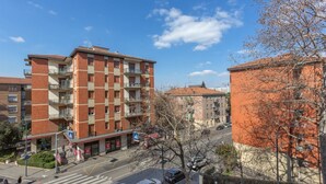 A multi-story residential building with balconies, a pedestrian crossing, and a clear blue sky.