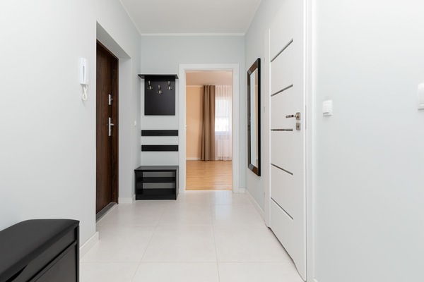 Hallway with coat racks and doors, leading to different rooms within the apartment.