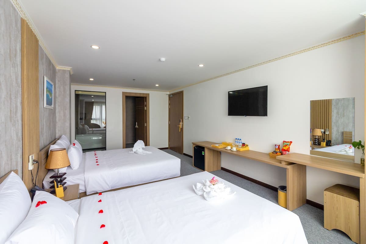 Una habitación de hotel con dos camas, un escritorio, un televisor y un espejo.